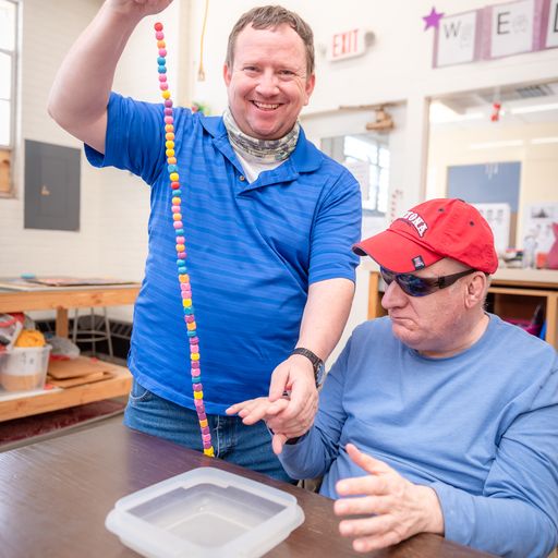 Man assisting a blind man at a desk